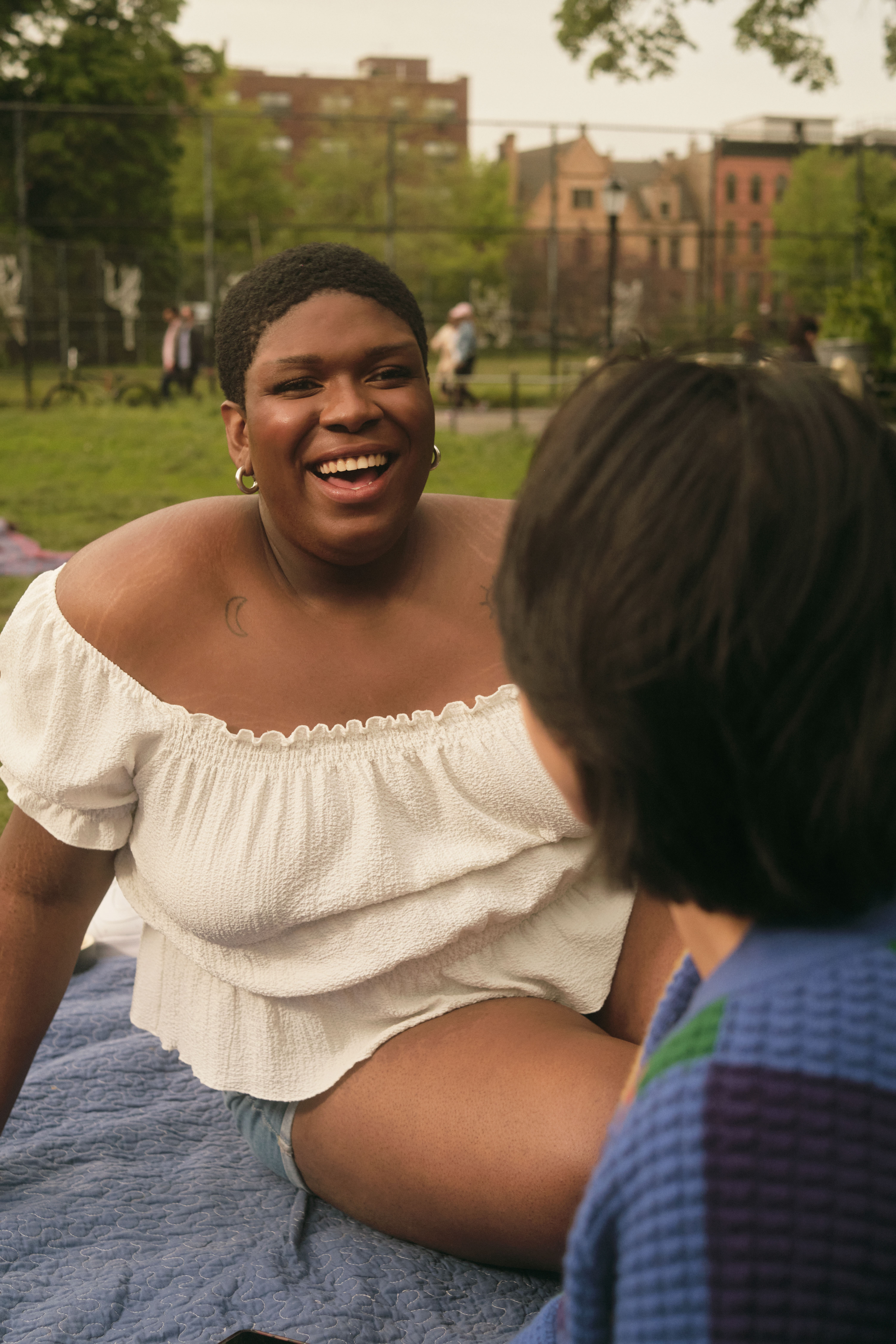 A non-binary trans woman laughing in a park